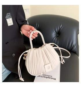 Detail of cream pleated bucket bag showing soft leather texture and drawstring design