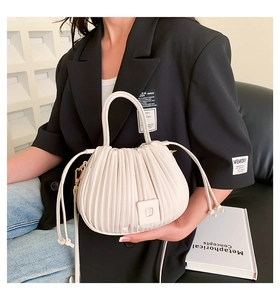Close-up of pleated beige cloud bucket bag with soft drawstring details and handle