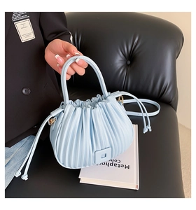 Macro view of light blue pleated bucket bag with drawstring closure and square buckle