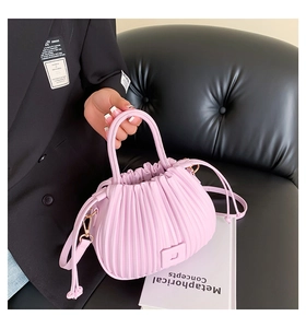 Detailed view of pink pleated bucket bag with gold hardware and drawstring closure
