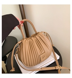 Detail of beige pleated bucket bag with leather texture and square buckle accent