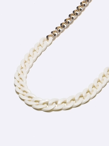 Dettaglio di catena in metallo dorato con maglie in acrilico color crema