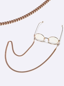 Detail view of golden V-shape arrow chain link texture for fashion eyewear