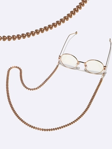 Detail of golden heart-shaped eyewear chain with polished metal links and secure loops