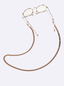 Close-up of golden heart-shaped eyewear chain with silicone loops on thin metal glasses
