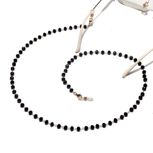 Detailed macro view of black crystal beaded eyewear chain with golden metal connectors