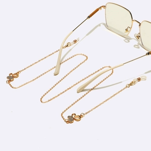 Detail of gold eyewear chain with rhinestone butterfly charms and clear rubber loops