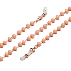 Close-up of faceted pale orange crystal beads with gold lobster clasps and rubber loops