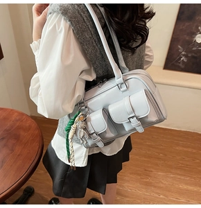 Detail of light blue multi-pocket shoulder bag with metal buckles and a bear charm