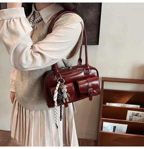 Detail of burgundy vintage underarm bag with multi-pockets and cute bear charm