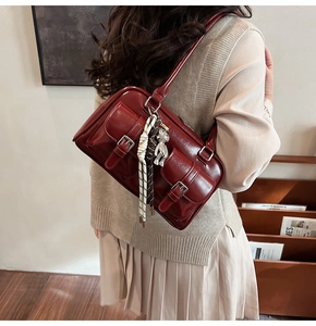Close-up of wine red retro underarm bag with silver buckles and a cute bear charm