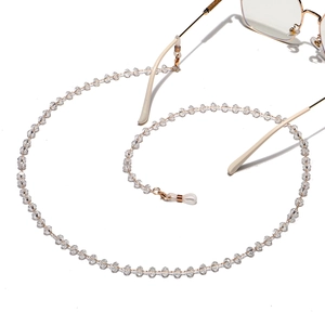 Macro detail of faceted crystal beads and gold metal links on a stylish eyeglass chain
