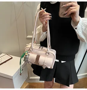 Detail of light pink PU leather Boston bag featuring dual front pockets and silver bear charm
