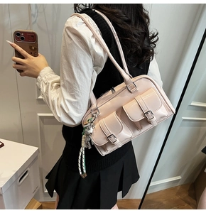 Detail of pink faux leather shoulder bag featuring double pockets and a bear charm
