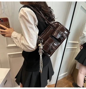 Detail view of deep brown glossy patent leather shoulder bag with vintage front pockets