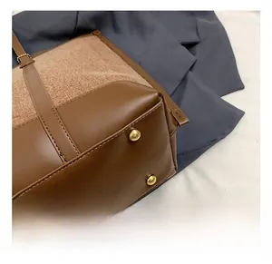 Détails des pieds en métal doré et des coutures d'un sac cabas en cuir marron