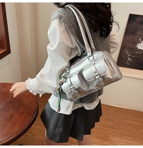 Detail of silver metallic shoulder bag with multi-pocket design and cute bear charm pendant