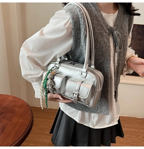 Detail of silver metallic shoulder bag featuring functional multi-pockets and a cute bear charm