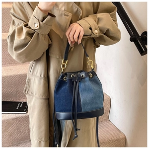 Close-up of denim bucket bag showing patchwork fabric details and leather trim