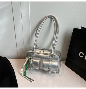 Close-up of metallic silver Boston bag featuring dual buckled pockets and a bear charm
