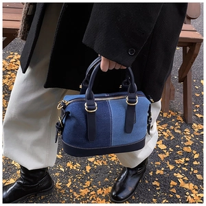Detail of denim patchwork Boston bag featuring white stitching and gold-tone hardware
