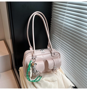 Detail of light pink vintage shoulder bag with dual utility pockets and metal bear charm