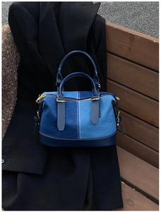 Detailed view of patchwork denim handbag featuring blue leather trim and golden hardware