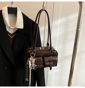 Detail of dark brown glossy shoulder bag with twin front pockets and silver zippers