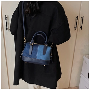 Detail of color-block denim Boston bag with gold hardware and leather straps shown on model
