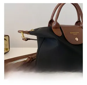 Detail of black nylon tote bag with brown snake-pattern leather handle and gold hook