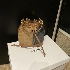 Detail of color-block bucket bag featuring golden brown glitter and dark grey panels