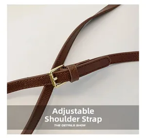 Detail view of brown pebbled leather shoulder strap with adjustable gold buckle