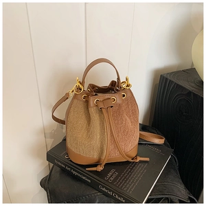 Detail of the drawstring bucket bag with leather stitching and golden metal hardware