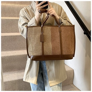 Détail d'un grand sac cabas en tissu texturé beige et poignées en cuir marron