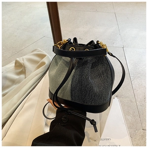 Detail of two-tone denim bucket bag with gold hardware and black leather drawstring