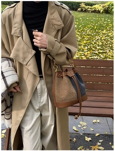 Detail of vintage denim bucket bag with brown leather base and gold chain handle outdoors