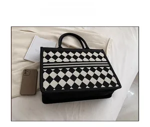 Close-up of black and white checkered jacquard tote bag with sturdy handles