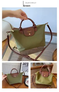 Detail of army green nylon tote bag featuring brown leather handles and gold metal snap button