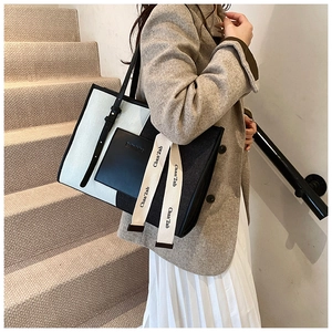 Chic denim tote bag with contrast stitching and leather strap shown in a street style view