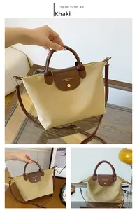 Detail of khaki oxford cloth tote bag with brown leather handles and snap button flap