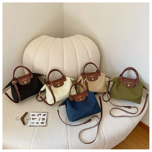 Five colors of nylon tote bags with leather handles and straps in a minimalist display