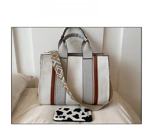 Détail du sac cabas en toile avec poignées en cuir et bandoulière large à motifs ethniques
