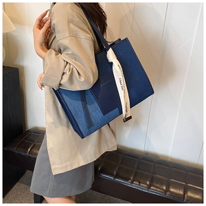 Detail of blue denim tote bag with leather patch and silk scarf on a model