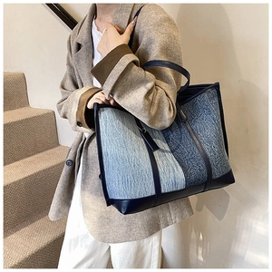 Grand sac cabas en denim patchwork bleu avec poignées en cuir porté par un mannequin
