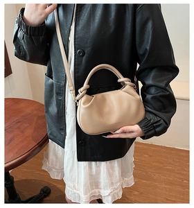 Detail of beige pleated bucket bag with braided handle and detachable shoulder strap