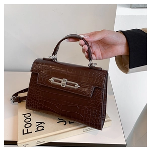 Close-up of the dark brown crocodile embossed texture and silver metal lock on the bag