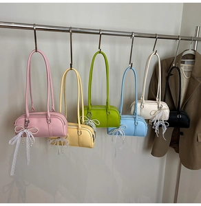 Row of colorful lychee grain Boston bags with pearl lace bow charms on a metal rack