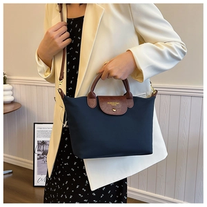 Detail of navy nylon tote bag with brown leather handles and adjustable shoulder strap