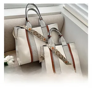 Détails du sac cabas en toile crème avec finitions en cuir marron et bandoulière rétro
