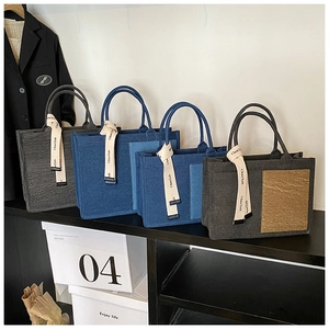 Detail view of four textured tote bags in grey and blue with decorative branded ribbons